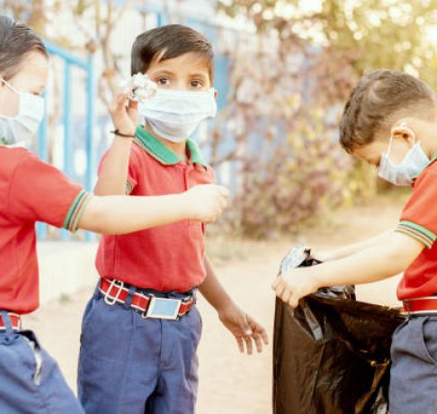 Group of children volunteers picking up, cleaning trash at school - concept of school kids or classmates collecting trash, charity environment