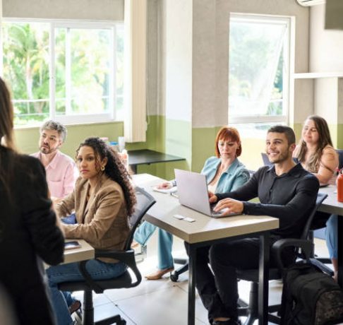 Group of adult students paying attention to female lecturer in classroom